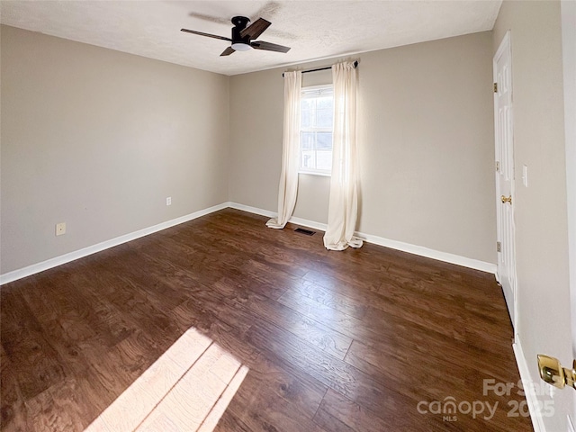 unfurnished room featuring ceiling fan, visible vents, dark wood finished floors, and baseboards