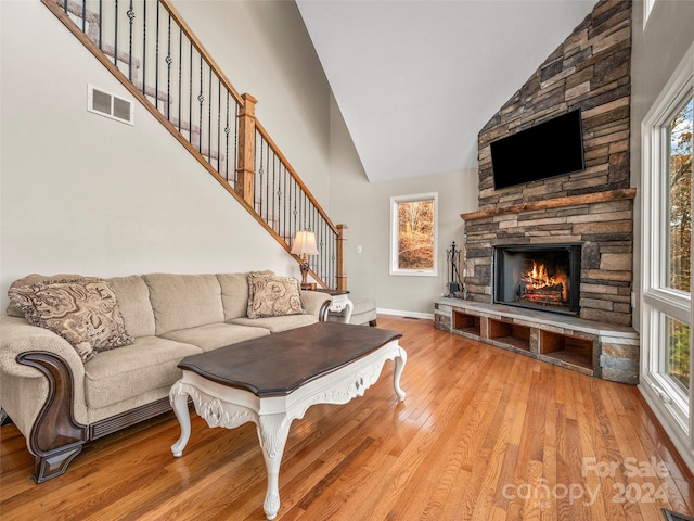 living room featuring a healthy amount of sunlight, light wood-type flooring, and high vaulted ceiling