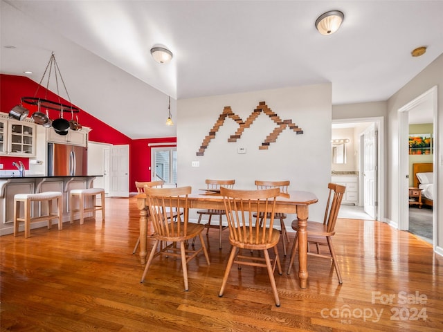 dining room with wood-type flooring, sink, and high vaulted ceiling