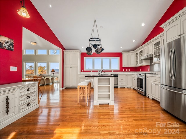 kitchen featuring decorative light fixtures, a healthy amount of sunlight, a kitchen island, and appliances with stainless steel finishes