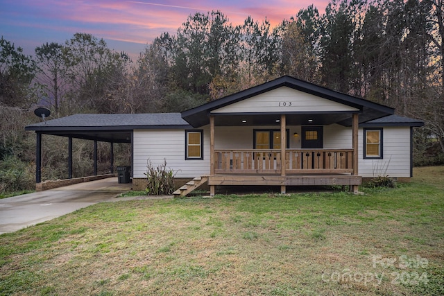 view of front of home with a lawn, a porch, and a carport