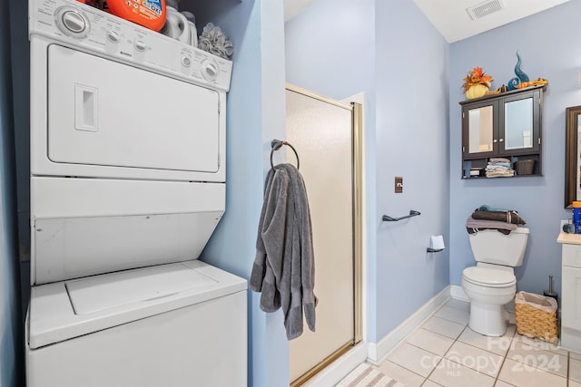 washroom with light tile patterned floors and stacked washing maching and dryer