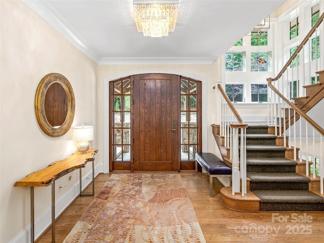 foyer featuring an inviting chandelier, ornamental molding, and wood-type flooring