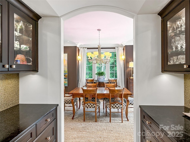 dining room featuring light colored carpet, ornamental molding, and an inviting chandelier