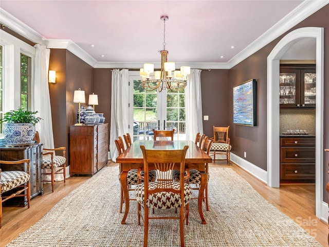 dining room featuring light wood-type flooring, crown molding, a chandelier, and a healthy amount of sunlight