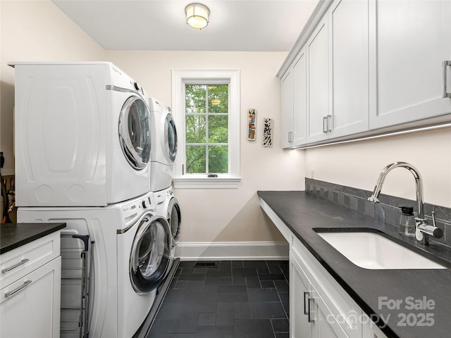 clothes washing area with cabinets, sink, and stacked washer / dryer