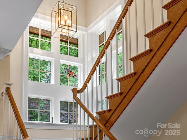 stairway with an inviting chandelier and a towering ceiling