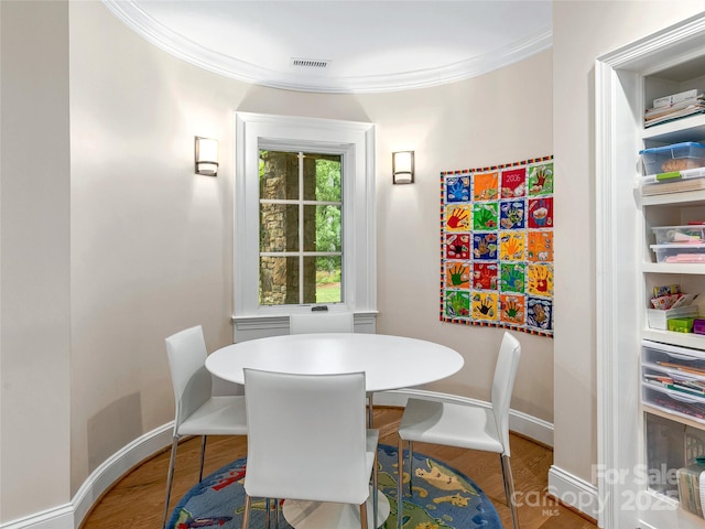 dining area with hardwood / wood-style flooring and crown molding