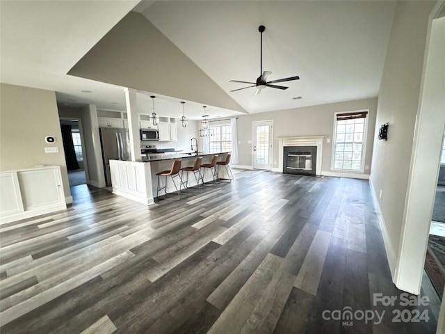 unfurnished living room featuring ceiling fan, dark hardwood / wood-style flooring, sink, and high vaulted ceiling