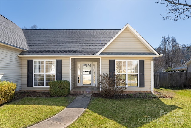 bungalow-style house featuring a shingled roof, a front lawn, and fence