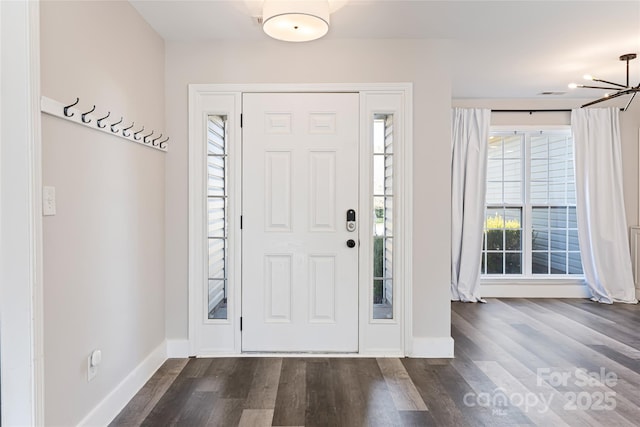 entrance foyer featuring visible vents, baseboards, dark wood-style flooring, and a chandelier