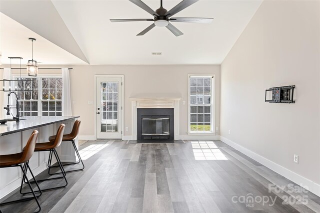 unfurnished living room with plenty of natural light, wood finished floors, visible vents, and a sink