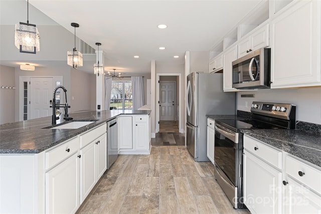 kitchen with light wood-style flooring, a sink, white cabinetry, stainless steel appliances, and a chandelier