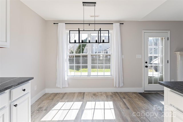 unfurnished dining area featuring light wood finished floors, plenty of natural light, and baseboards