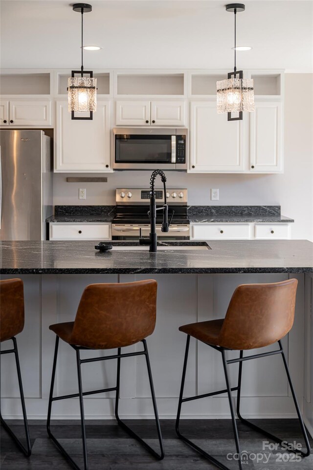 kitchen featuring a sink, stainless steel appliances, pendant lighting, and white cabinetry