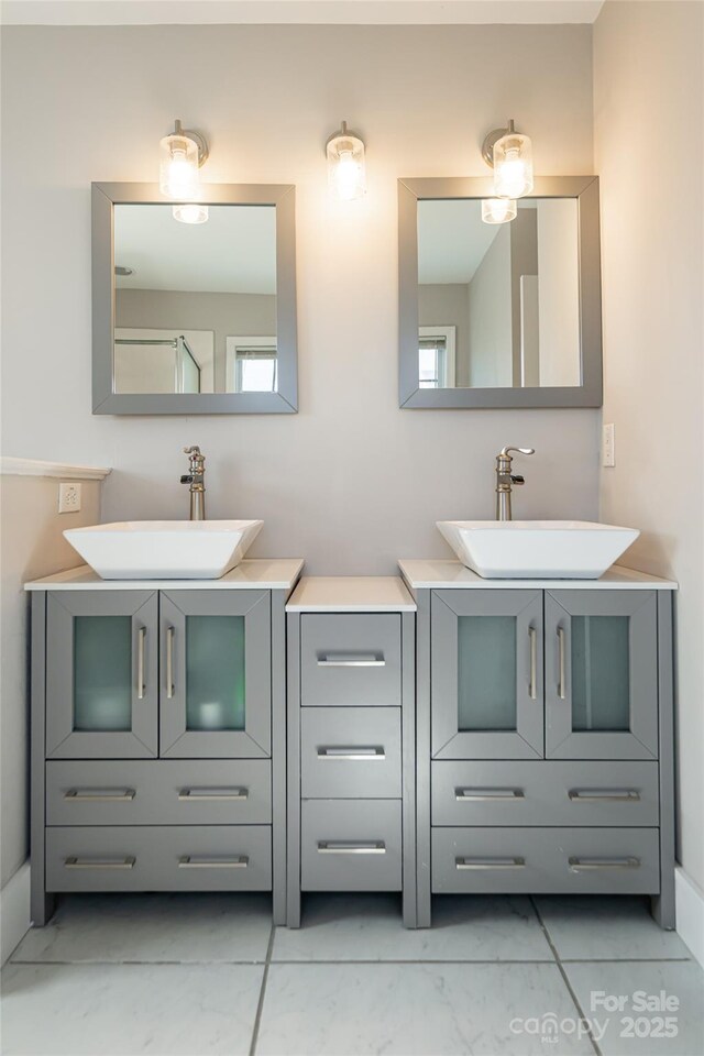 full bath with marble finish floor, two vanities, and a sink