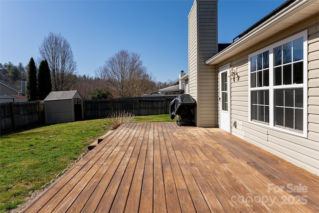 deck featuring a lawn, an outdoor structure, a fenced backyard, area for grilling, and a storage unit