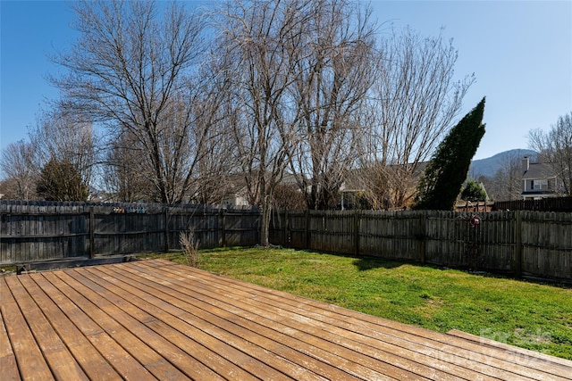 wooden terrace with a lawn, a mountain view, and a fenced backyard