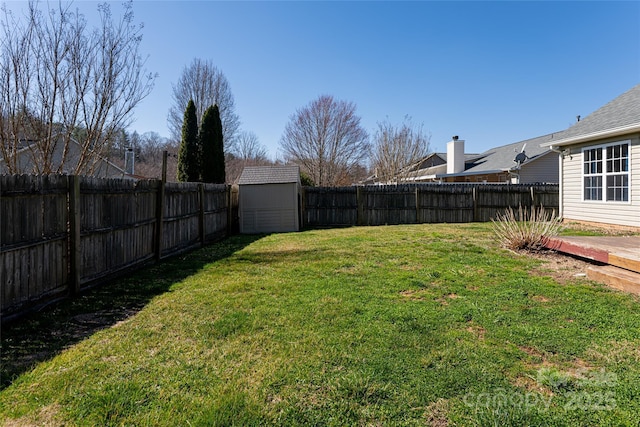 view of yard with an outbuilding, a fenced backyard, and a shed