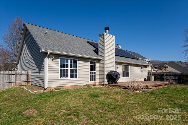 rear view of house with a yard, a fenced backyard, and a chimney