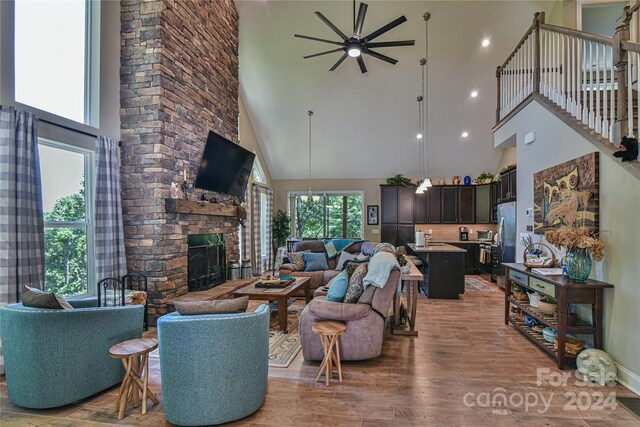 living room with hardwood / wood-style floors, ceiling fan, a fireplace, and a high ceiling