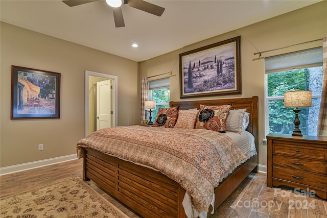 bedroom featuring ceiling fan, wood-type flooring, and multiple windows