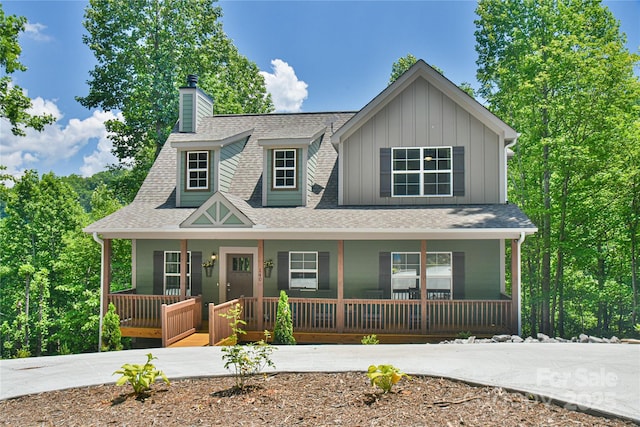 view of front of house with a porch, a chimney, board and batten siding, and a shingled roof