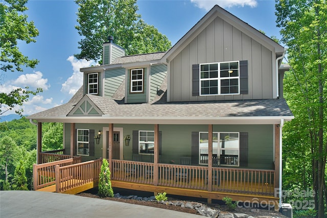 view of front of house with board and batten siding, covered porch, and a shingled roof