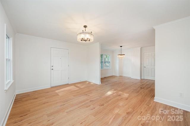 spare room featuring crown molding, a chandelier, and light hardwood / wood-style floors