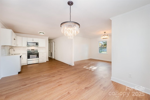 kitchen featuring stove, white cabinets, sink, pendant lighting, and a chandelier