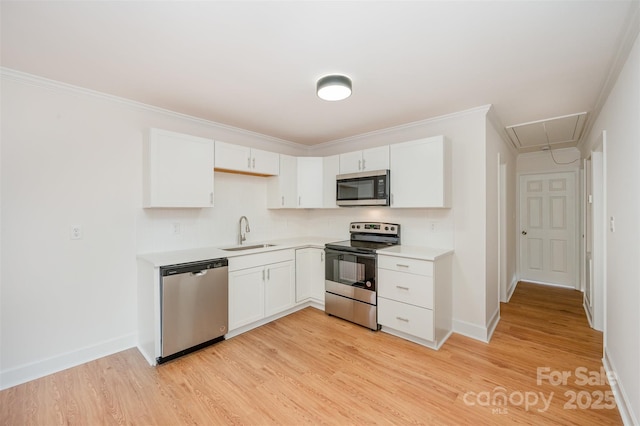 kitchen featuring appliances with stainless steel finishes, light wood-type flooring, ornamental molding, sink, and white cabinetry