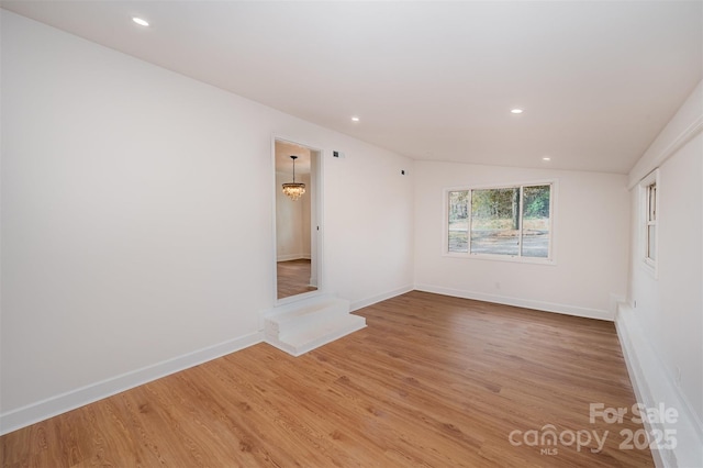 unfurnished room with wood-type flooring, lofted ceiling, and a notable chandelier