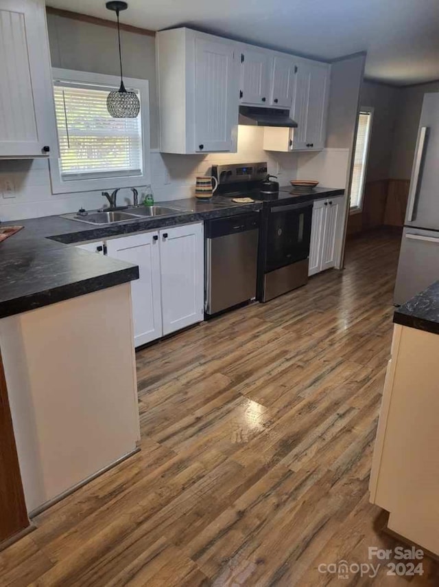 kitchen featuring white cabinetry, sink, pendant lighting, wood-type flooring, and appliances with stainless steel finishes