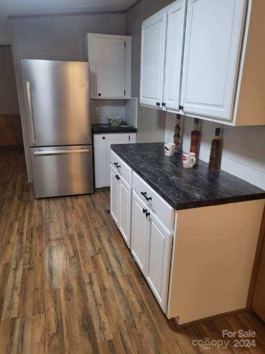 kitchen with white cabinetry, dark wood-type flooring, and stainless steel refrigerator