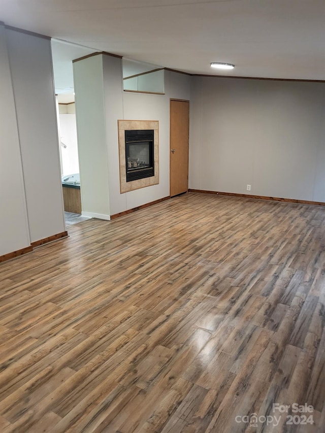 unfurnished living room featuring a tile fireplace and wood-type flooring