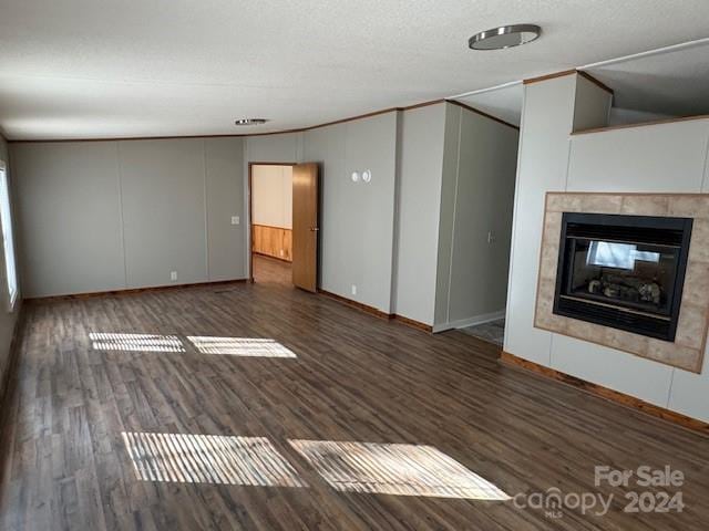 unfurnished living room featuring a textured ceiling, a tiled fireplace, and dark hardwood / wood-style floors