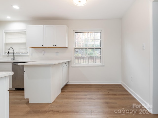 kitchen featuring dishwasher, white cabinets, sink, light hardwood / wood-style floors, and kitchen peninsula