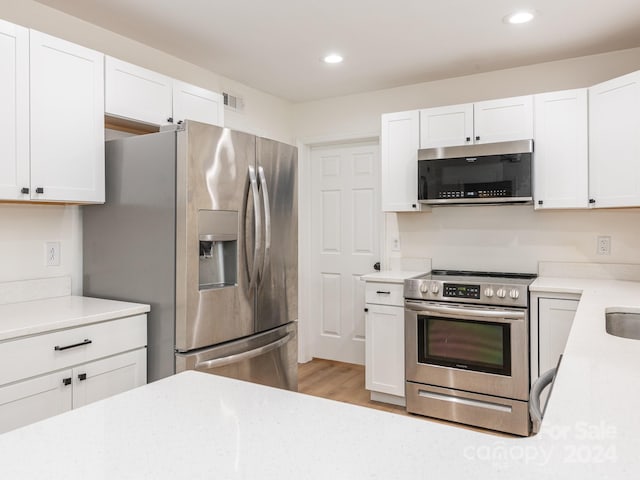 kitchen with white cabinetry, appliances with stainless steel finishes, and light hardwood / wood-style flooring