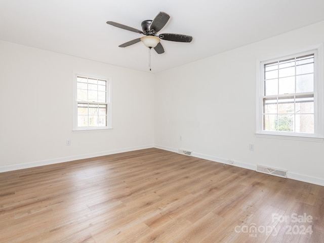 empty room featuring a wealth of natural light, ceiling fan, and light wood-type flooring