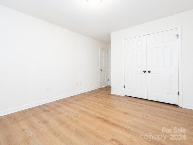 unfurnished bedroom with light wood-type flooring and a closet