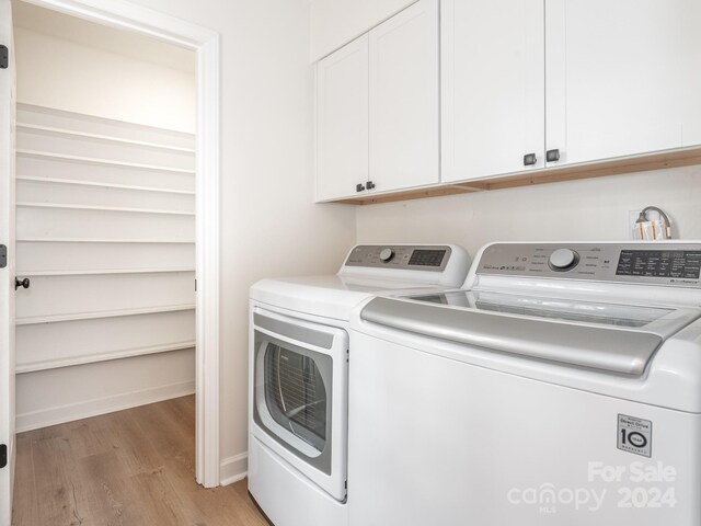 clothes washing area featuring cabinets, light wood-type flooring, and separate washer and dryer