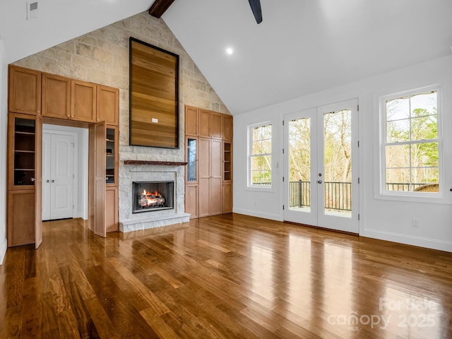 unfurnished living room with french doors, high vaulted ceiling, beamed ceiling, a fireplace, and hardwood / wood-style floors