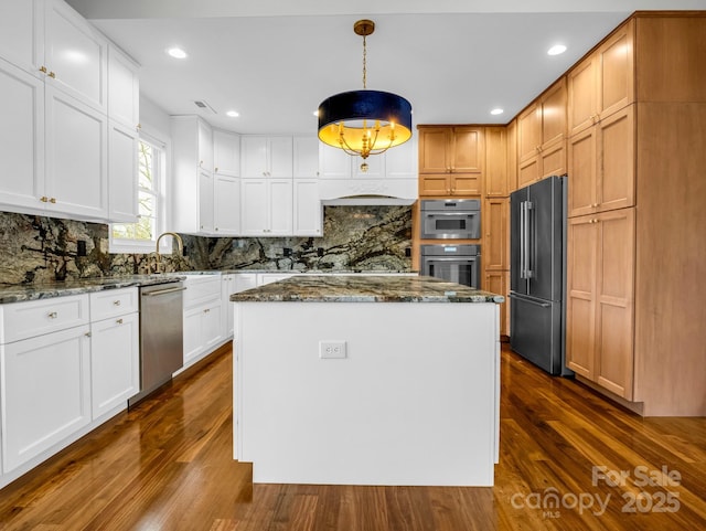 kitchen with white cabinetry, stainless steel appliances, a kitchen island, and pendant lighting