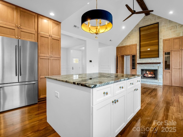 kitchen with white cabinetry, stainless steel fridge, dark stone counters, hanging light fixtures, and a center island