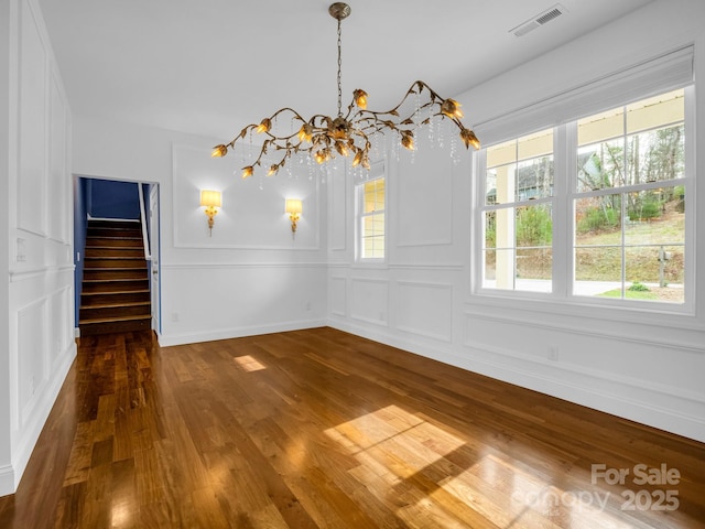 unfurnished dining area featuring an inviting chandelier and dark hardwood / wood-style floors