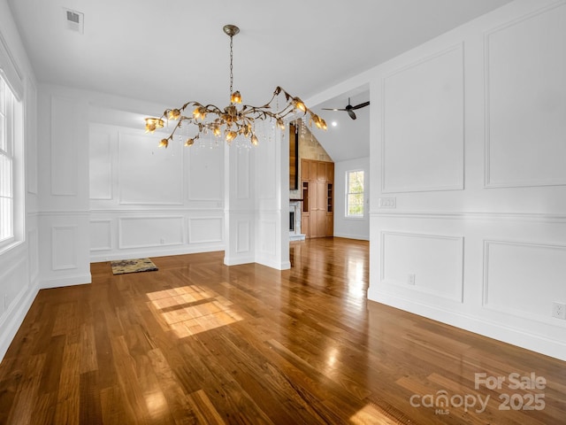 unfurnished dining area featuring wood-type flooring, vaulted ceiling, and a notable chandelier