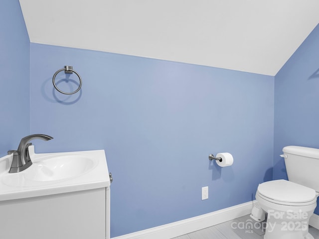 bathroom with vanity, vaulted ceiling, and toilet