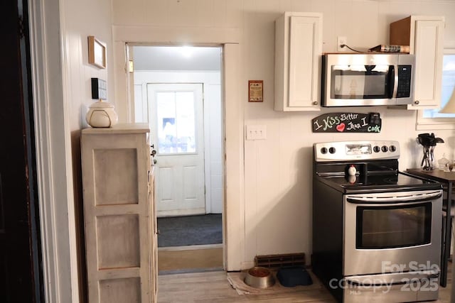 kitchen with light wood-type flooring, white cabinetry, and stainless steel appliances