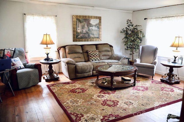 living room featuring wood-type flooring, ornamental molding, and a healthy amount of sunlight