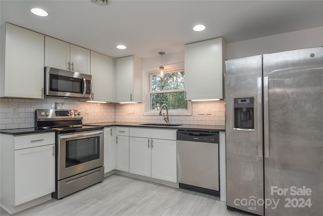 kitchen featuring sink, white cabinets, decorative light fixtures, and appliances with stainless steel finishes